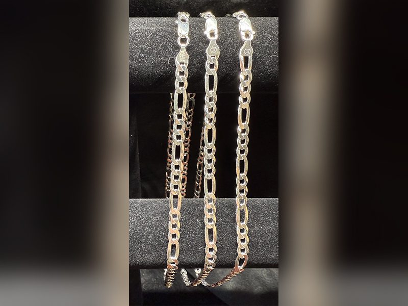 Three silver chains on black display stand.